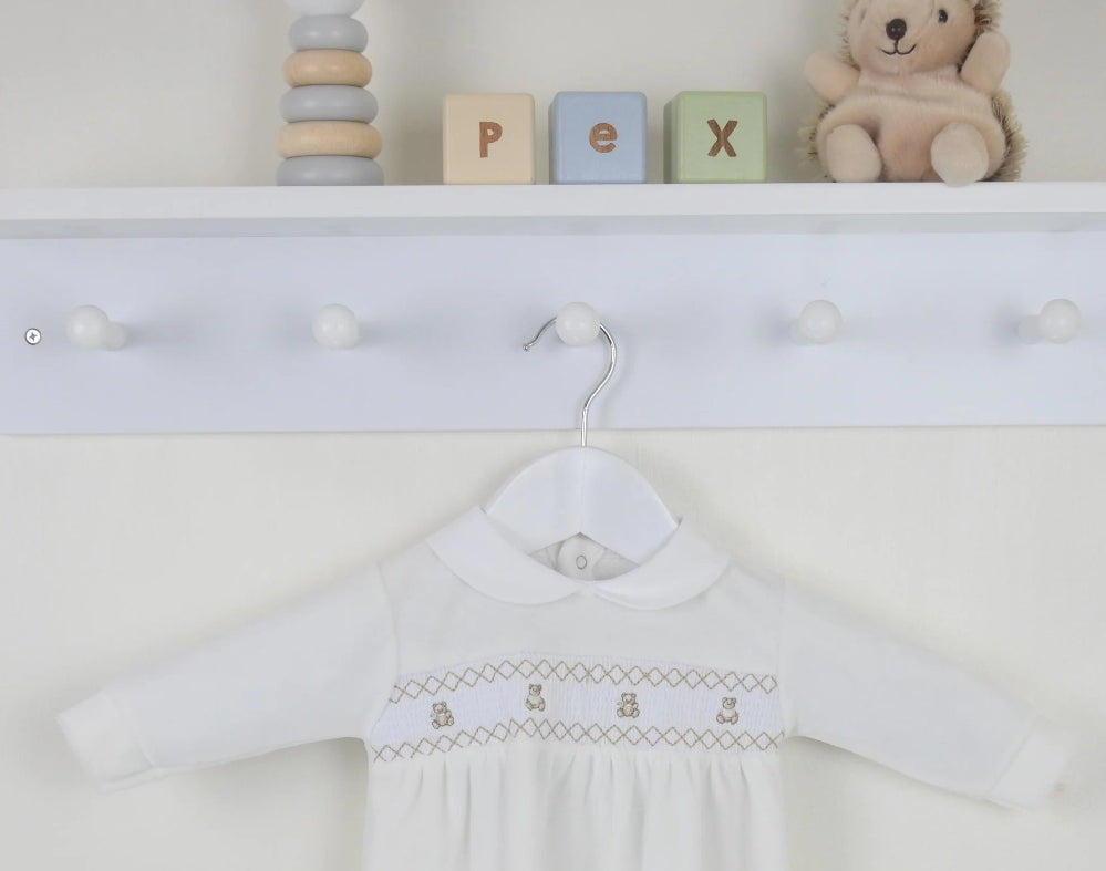 Flat lay of ivory velour baby outfit with teddy smocking and Peter Pan collar