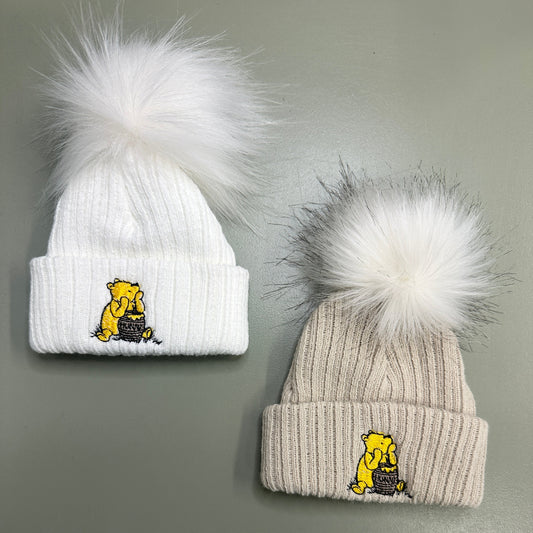 White and taupe Hunny Bear baby pom pom hats with embroidered bear motif