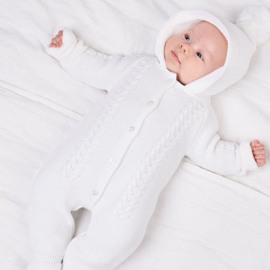 White knitted baby pramsuit with bobble hood by Dandelion – front view on hanger