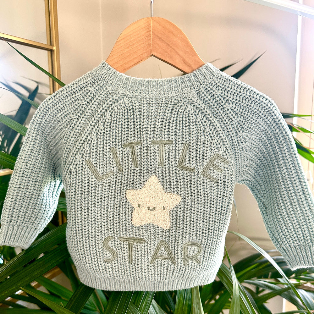 Close-up of green cardigan with “Little Star” and smiling star applique