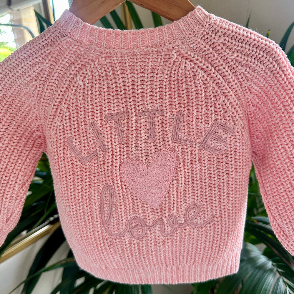Close-up of pink cardigan with “Little Love” and fluffy heart design
