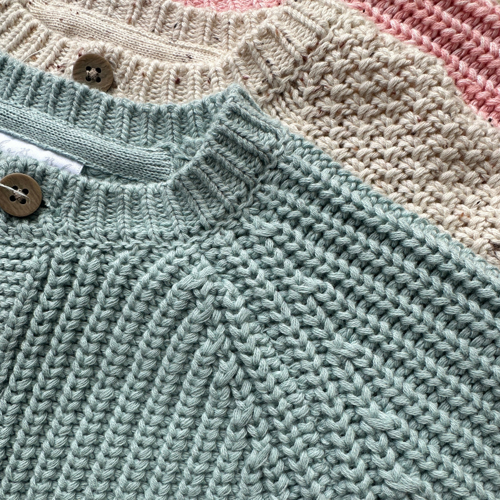 Three knitted baby cardigans in green, oatmeal fleck, and soft pink