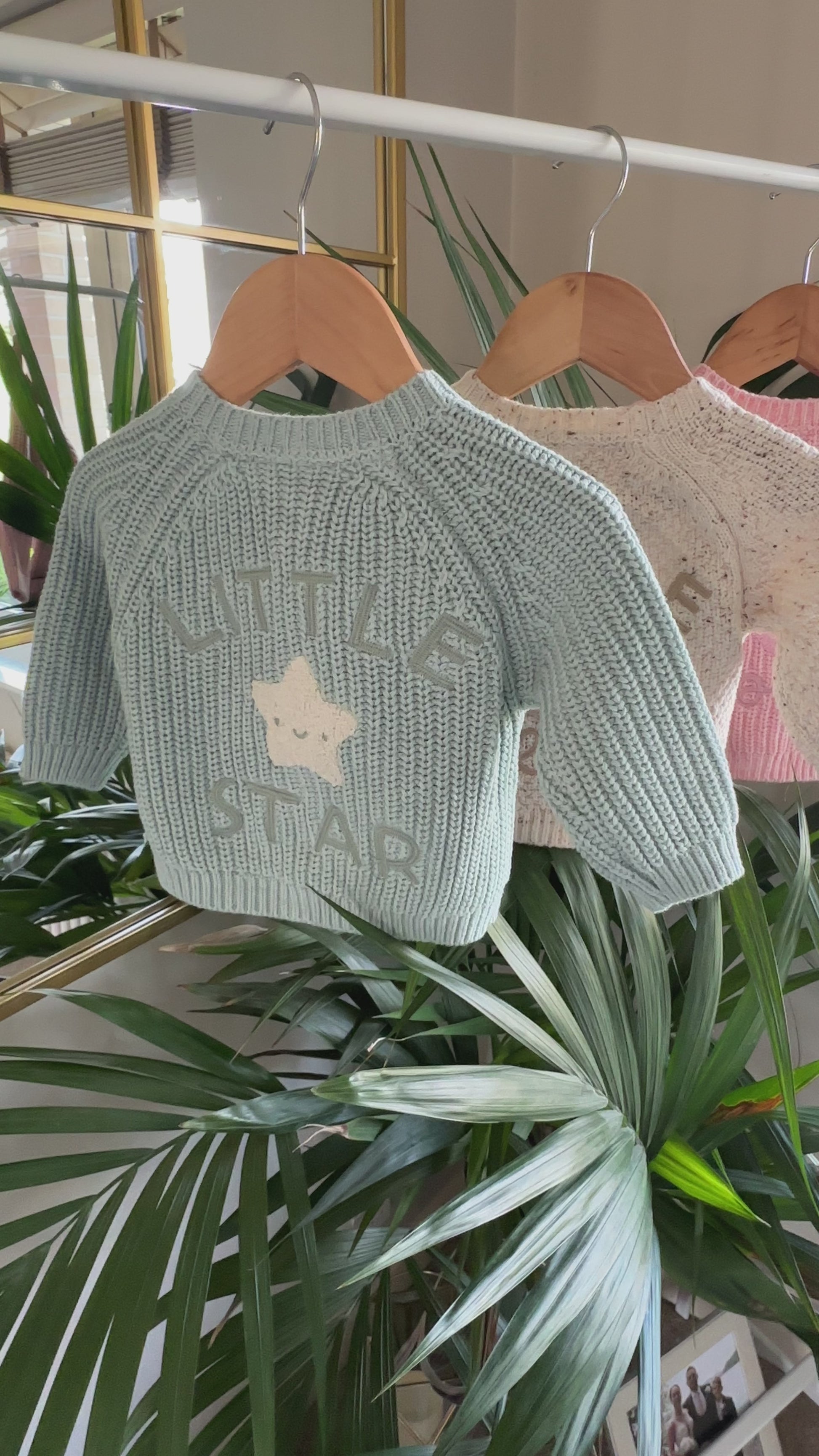 Three knitted baby cardigans in green, oatmeal fleck, and soft pink