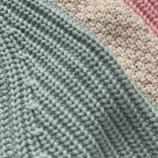 Three knitted baby cardigans in green, oatmeal fleck, and soft pink